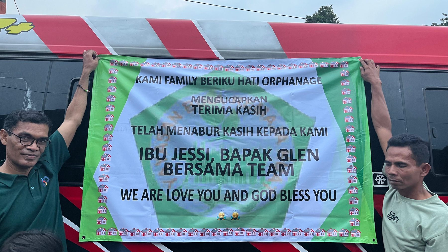 Orphanage staff holding a thank-you banner addressed to Ibu Jessi, Bapak Glen and team